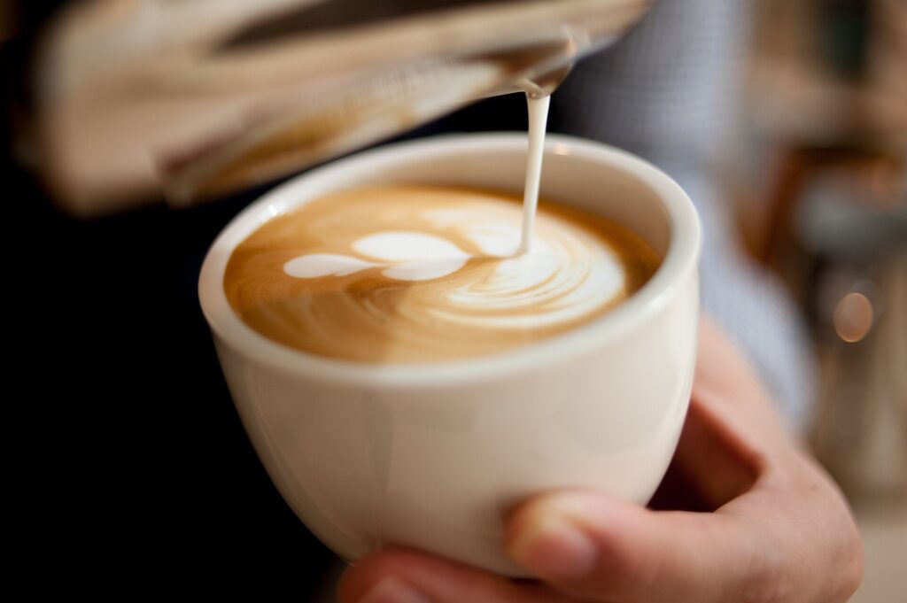 Milch wird in einen Cappuccino gegossen
